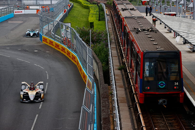 Formula E racing car on the outside track alongside a train in the London E-Prix