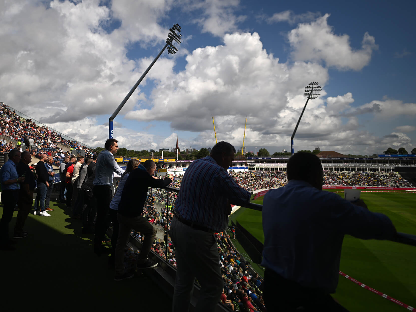 Guests on the Experience Club balcony overlooking the cricket pitch in hospitality at Edgbaston Stadium for the 2023 T20 Finals Day