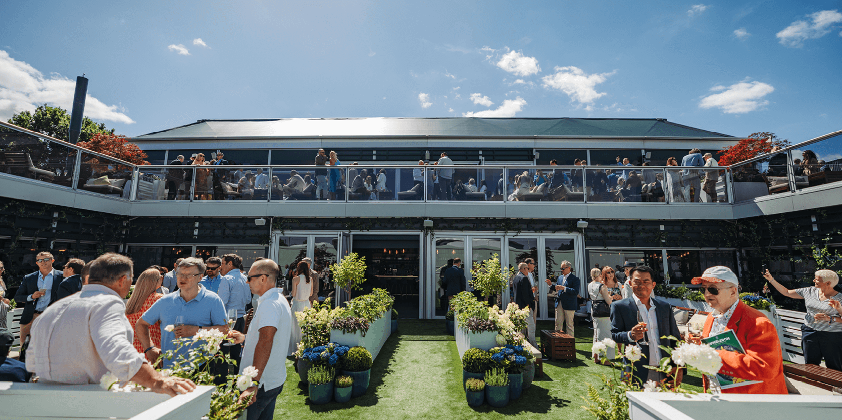 View of the garden and balcony area with guests chatting and enjoying the hospitality inside Rosewater Pavilion at The Championships, Wimbledon