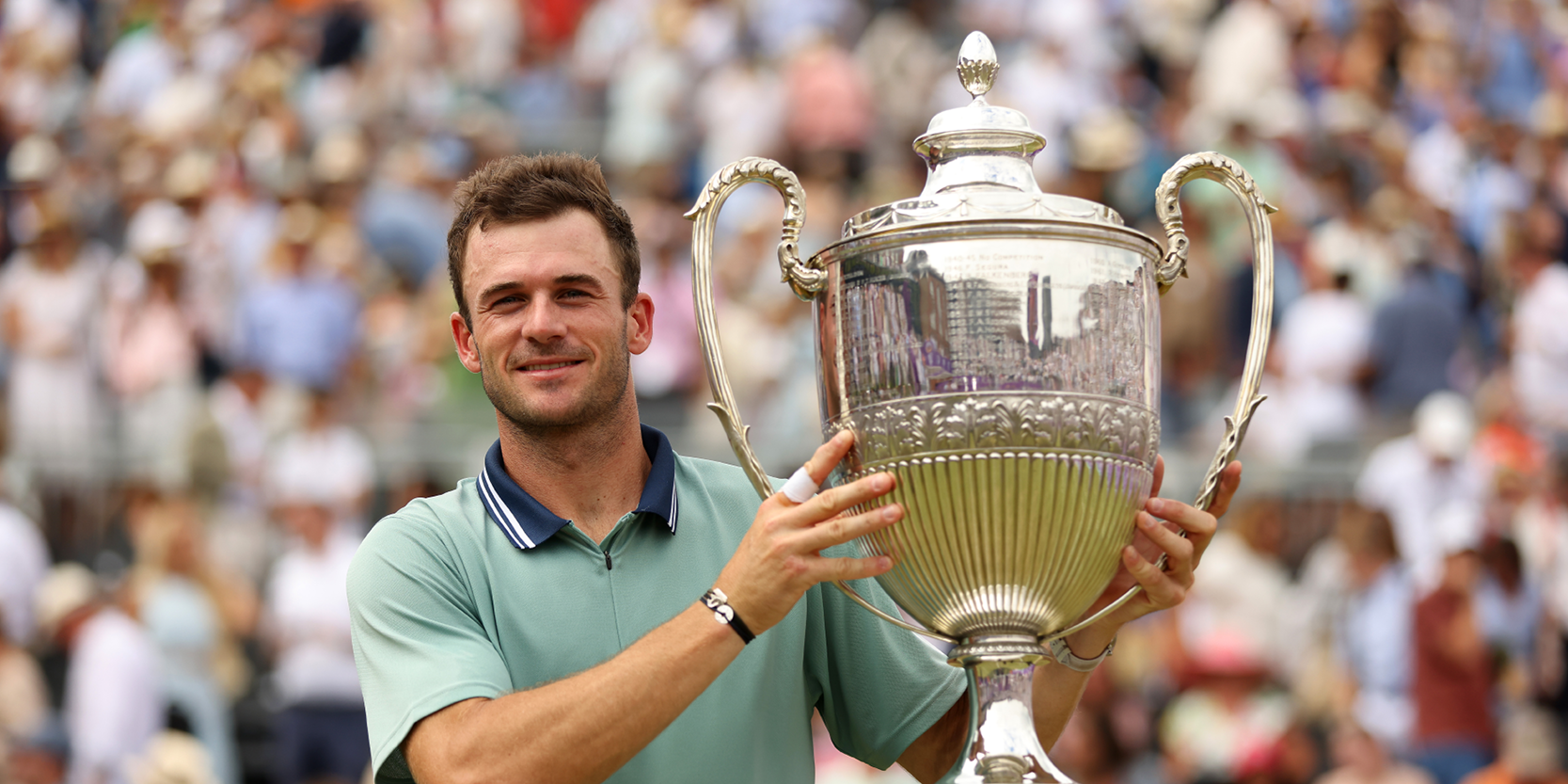 American tennis player Tommy Paul holding The Queen's Club Championships trophy after winning the final of 2024 on Centre Court