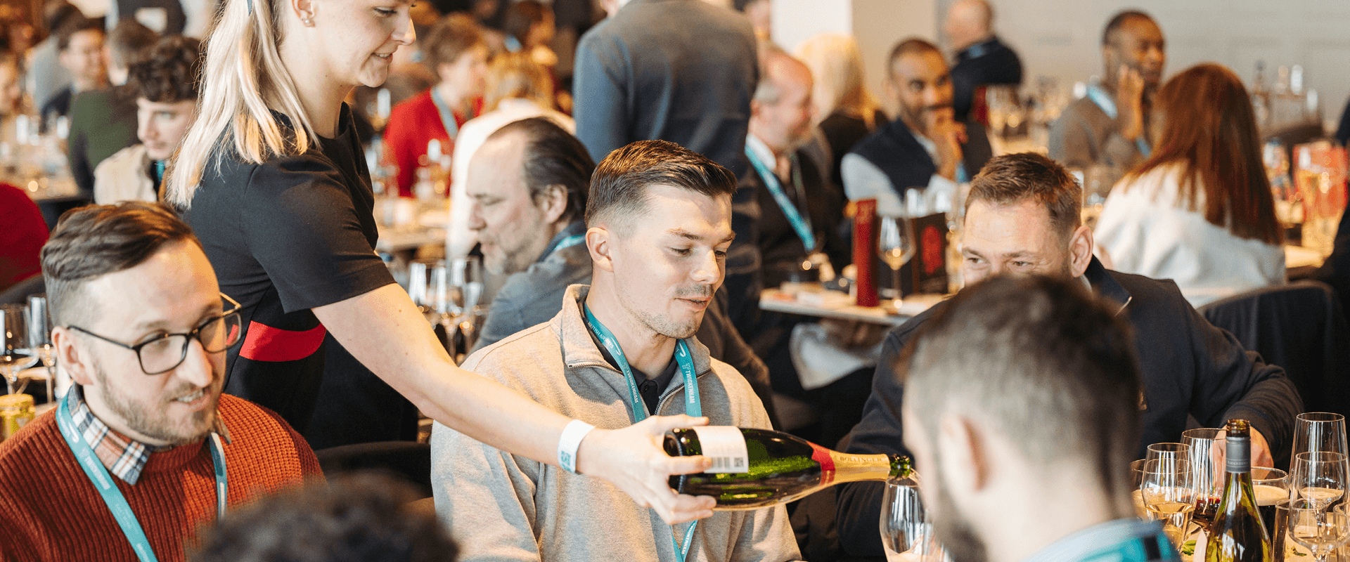 Hostess in The East Wing at Allianz Stadium hospitality pouring a glass of Champagne for a guest at a rugby match