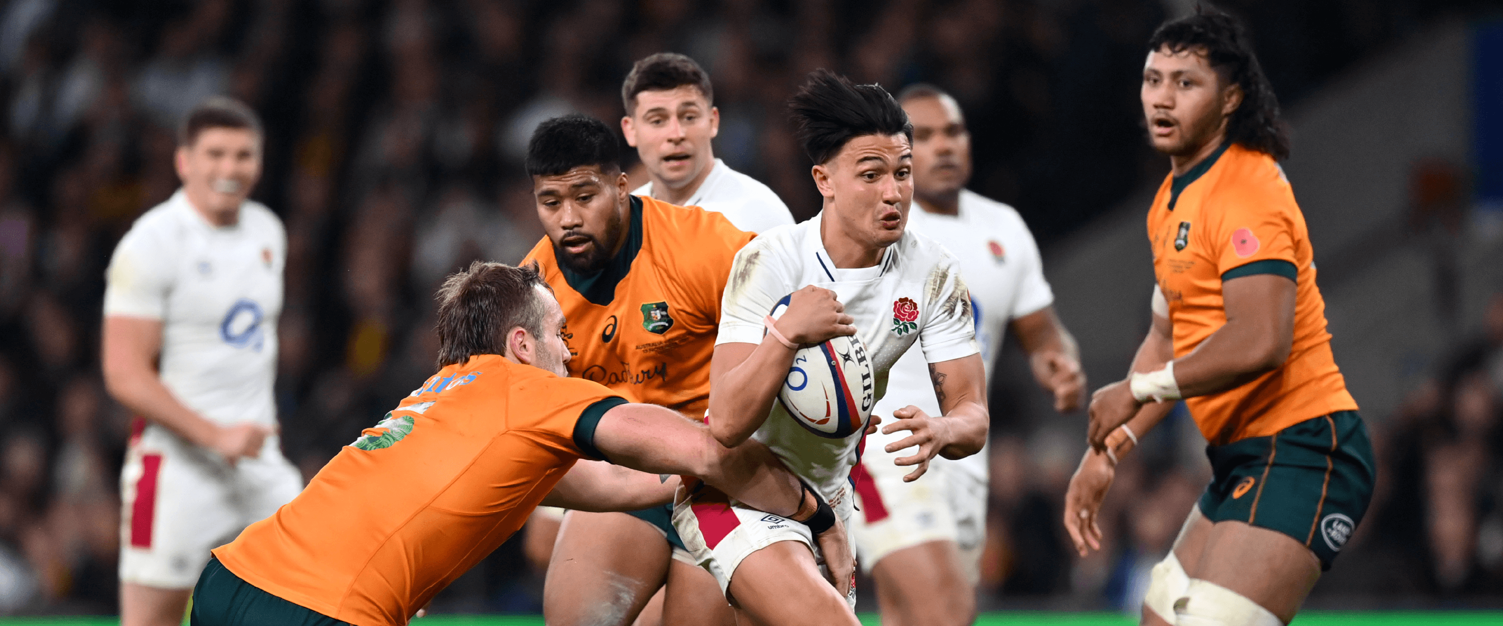 England Rugby player Marcus Smith running with the ball and being tackled during a match with Australia at Twickenham Stadium in the Autumn Nations Series