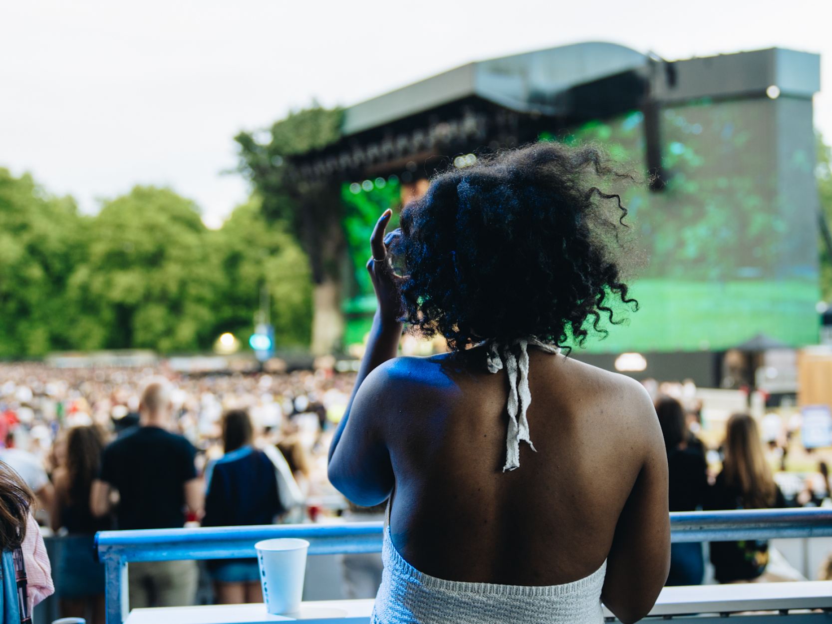A lady looking out at the stage and crowd from the Great Oak Roof Garden Terrace at BST Hyde Park
