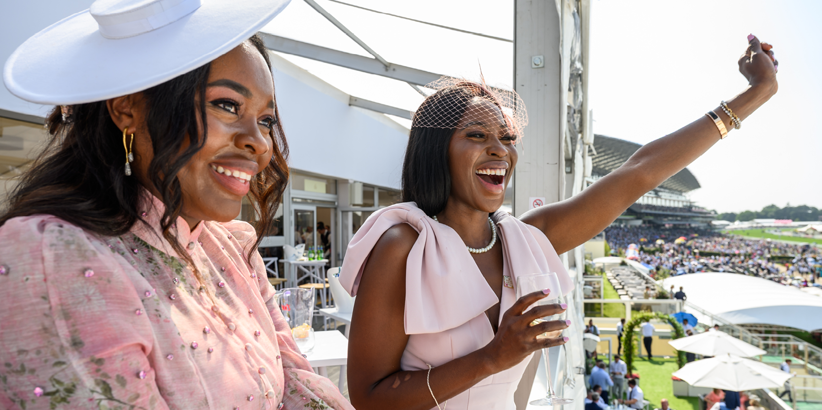 Ladies cheering from a viewing balcony at Royal Ascot during a race
