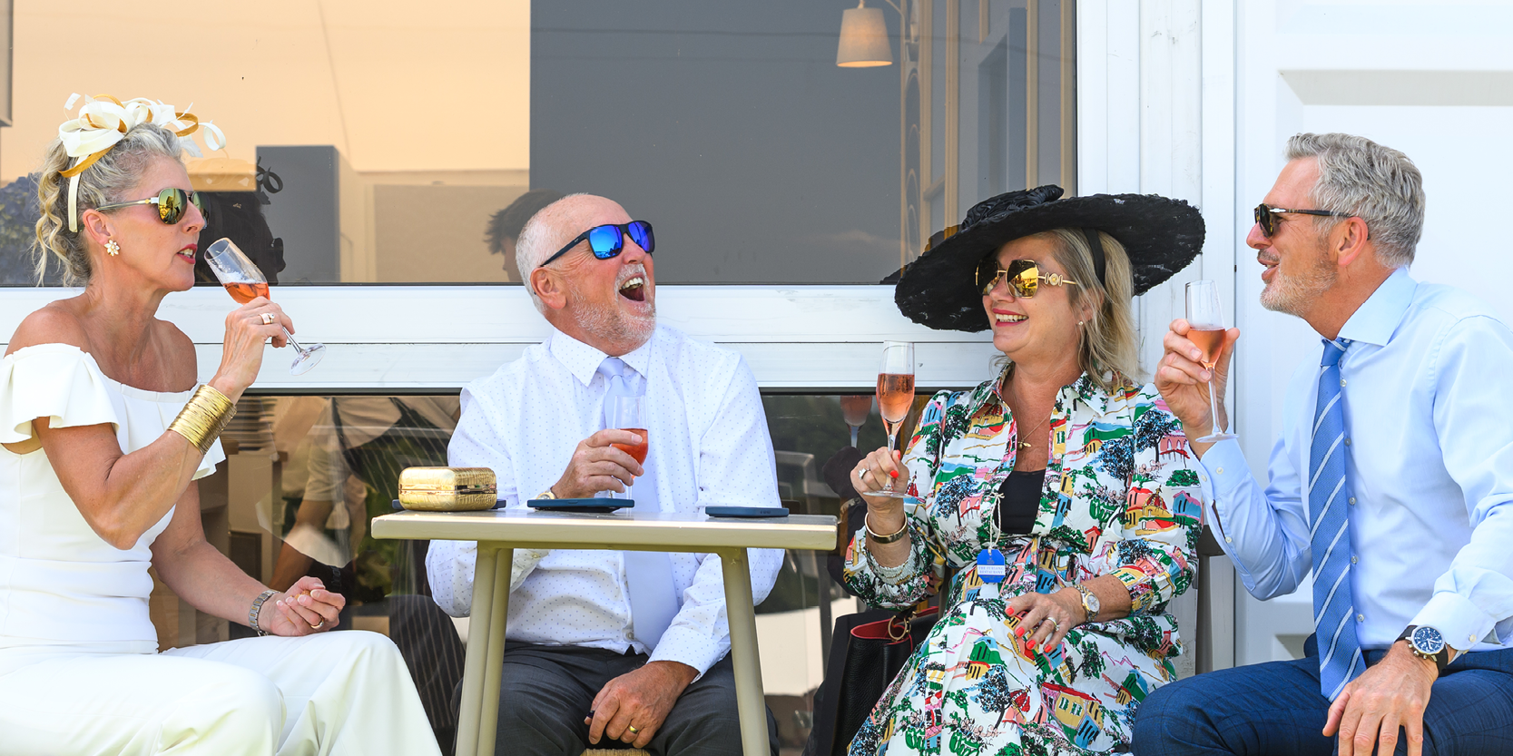 Guests smiling and laughing over a glass of Champagne in hospitality at Royal Ascot