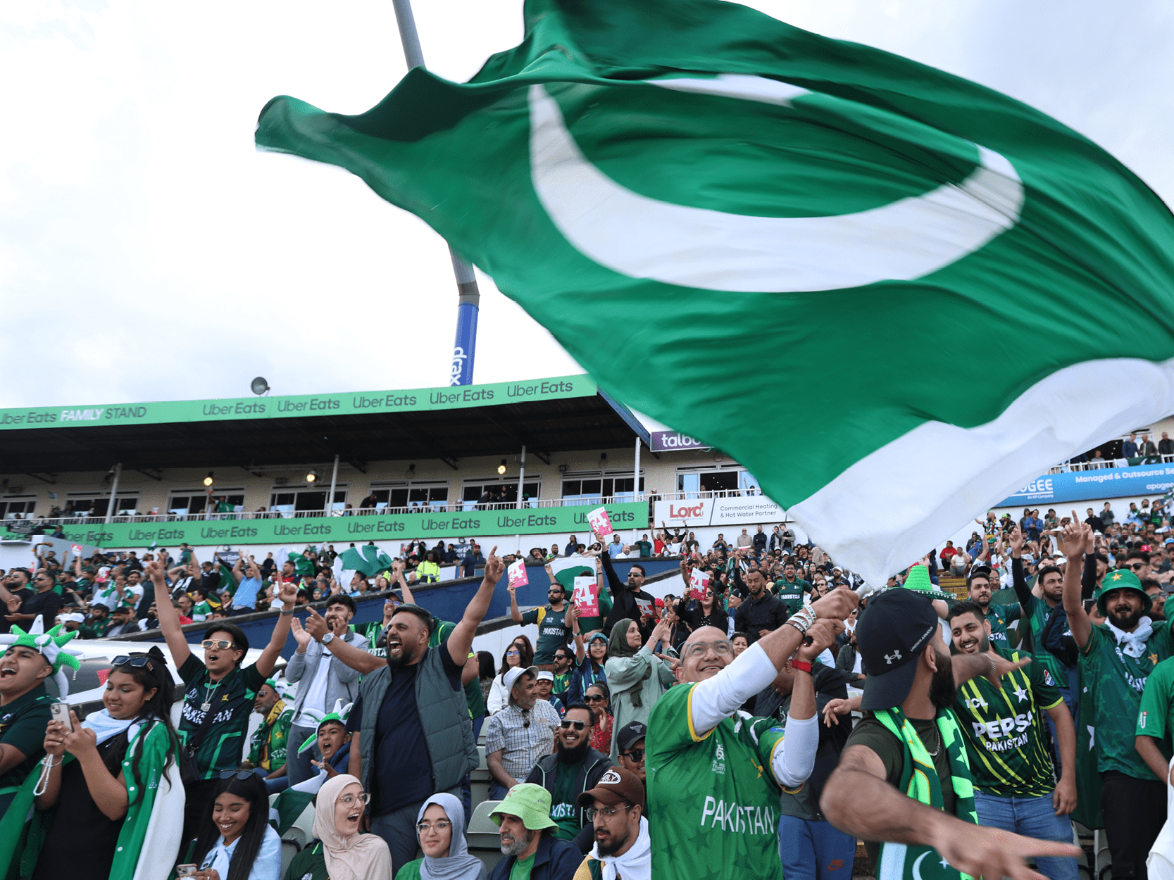 Pakistan cricket fans smiling in the crowd at Edgbaston and flying the Pakistan flag