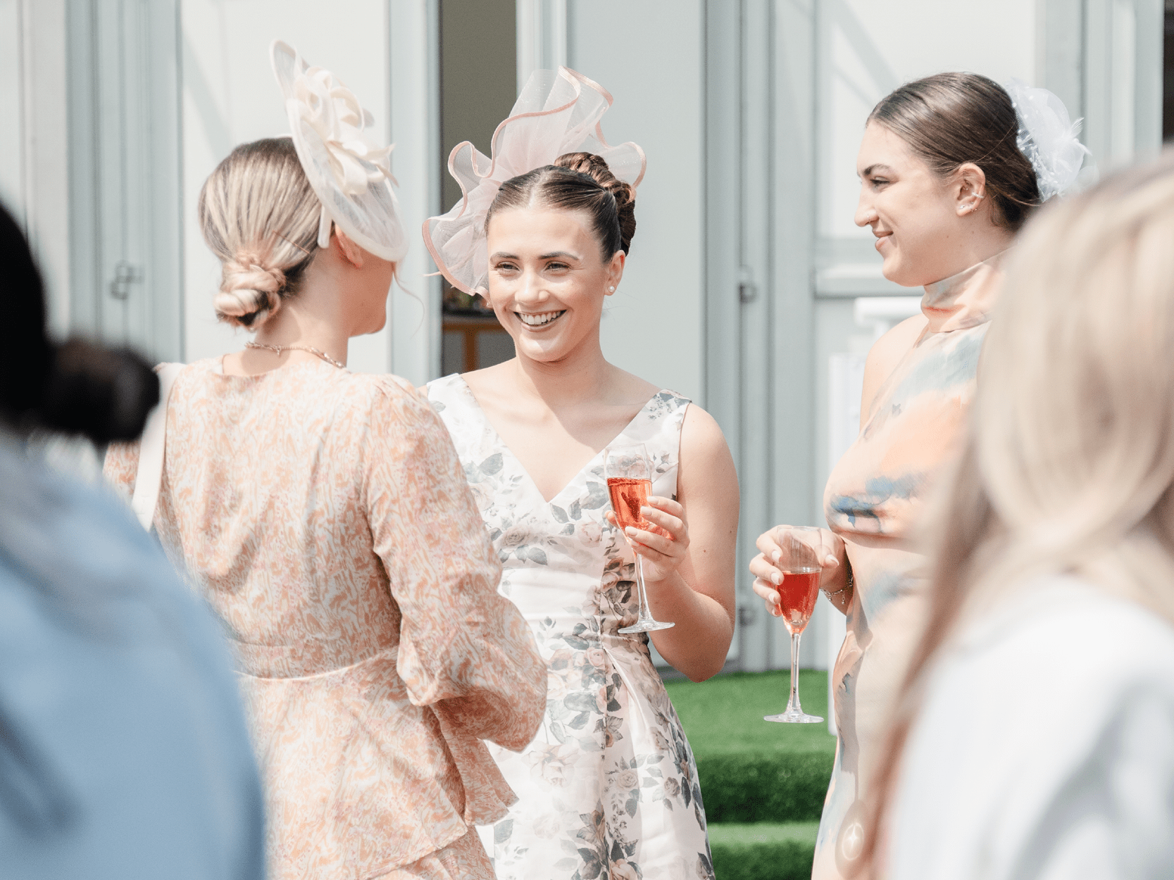 Guests smiling and chatting outside with drinks during Royal Ascot horse racing event in Ascot England