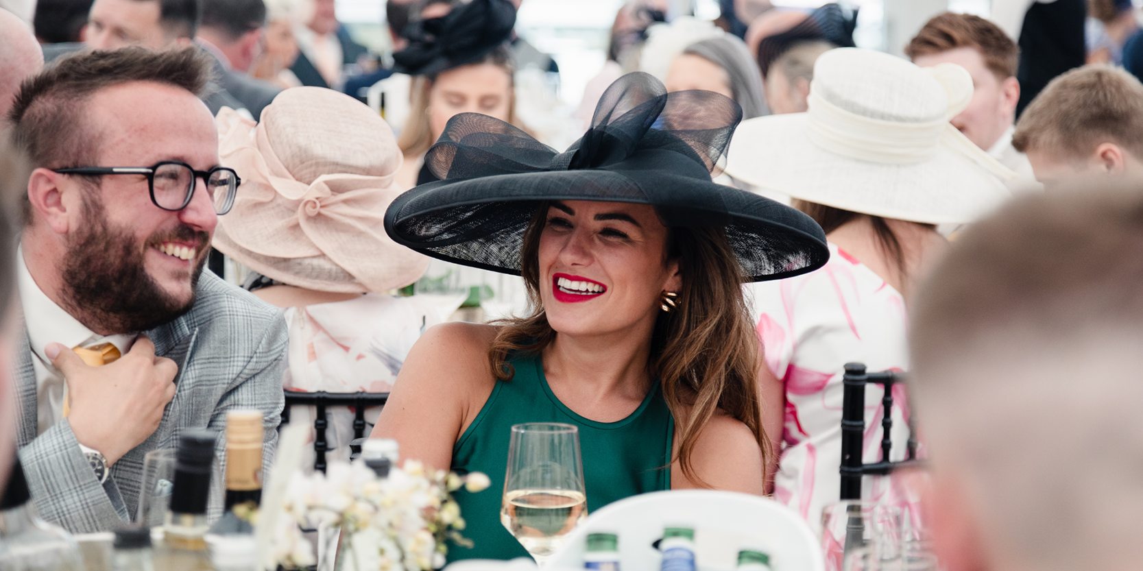 Man and lady smiling whilst sat down at their table at Royal Ascot horse racing event 