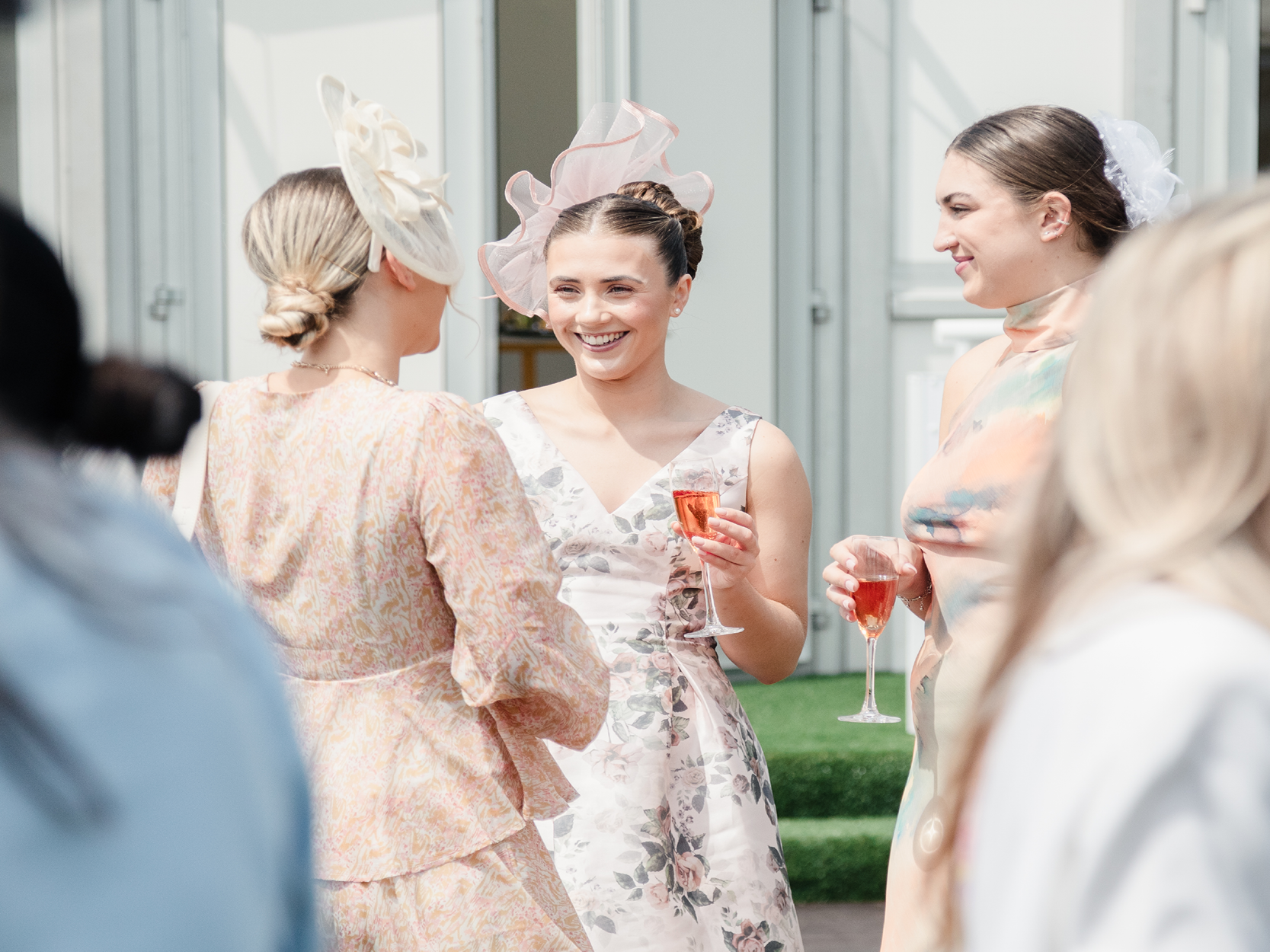 Ladies in dresses and fascinator hats at the Royal Ascot horse racing event in hospitality drinking Champagne and chatting