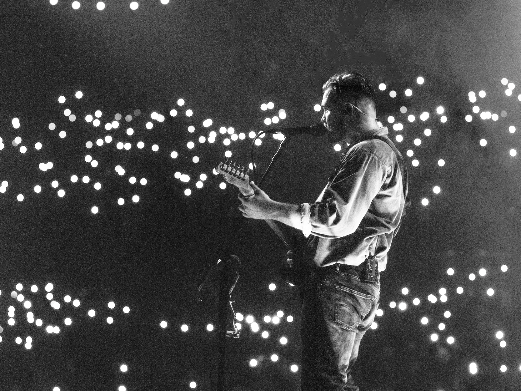 American country music artist Zach Bryan playing guitar and singing during a performance on stage