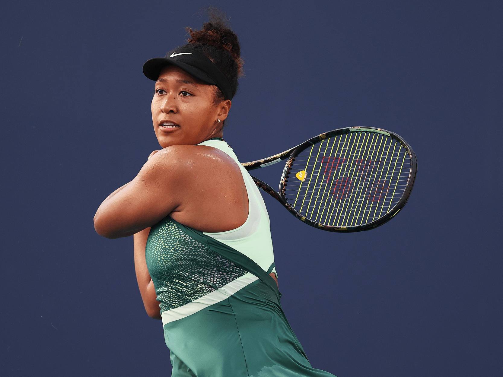 Women's tennis player Naomi Osaka hitting a ball during a shot in a tennis match