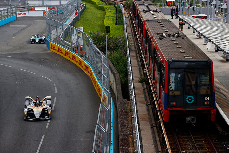 Formula E racing car on the outside track alongside a train in the London E-Prix