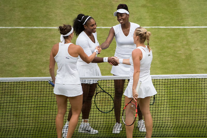 Venus and Serena Williams shaking their opponents hands at the end of a match at Wimbledon