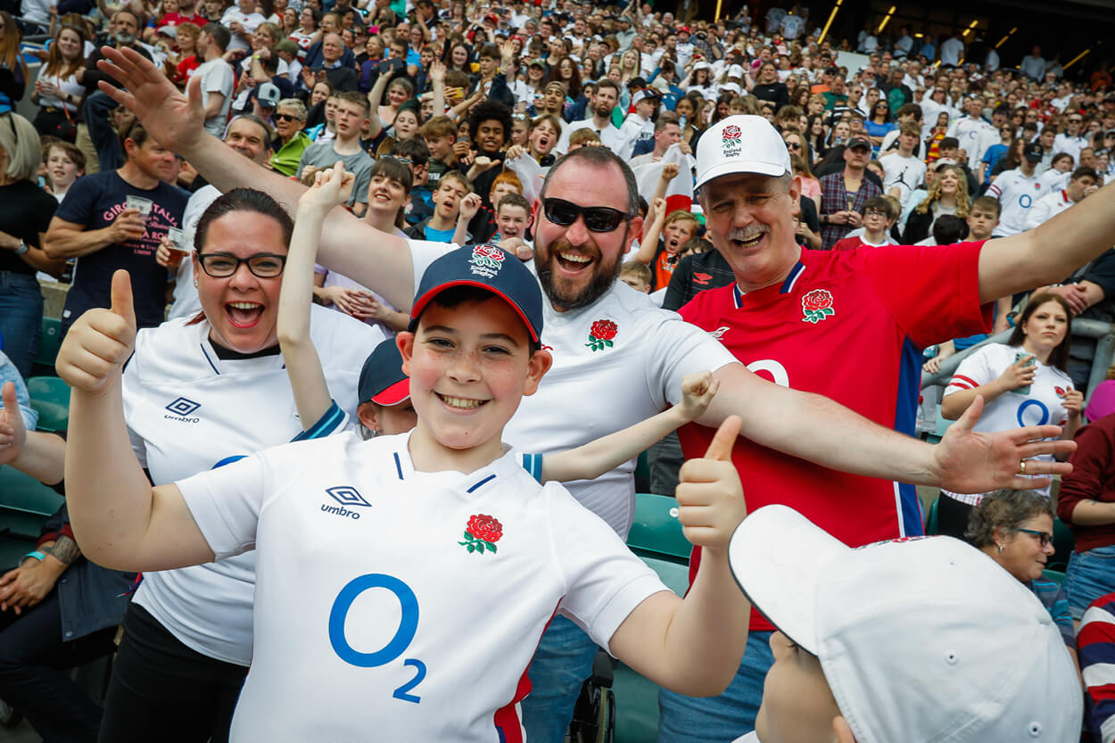 Red Roses fans cheering and smiling in the crowd at Twickenham Stadium