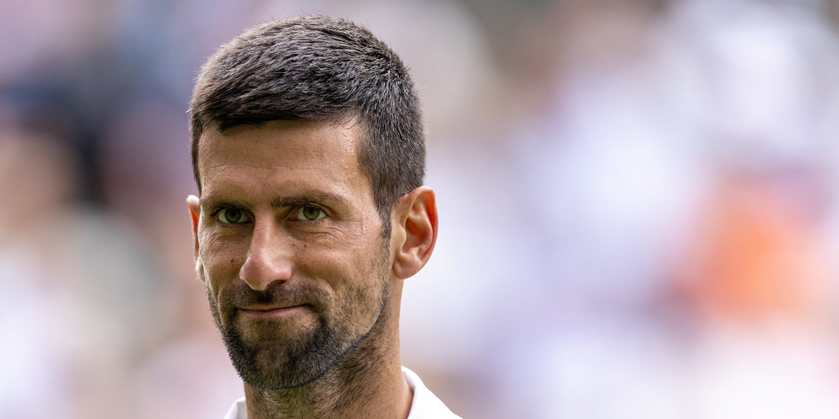Tennis player Novak Djokovic smiling during a match on Centre Court at Wimbledon