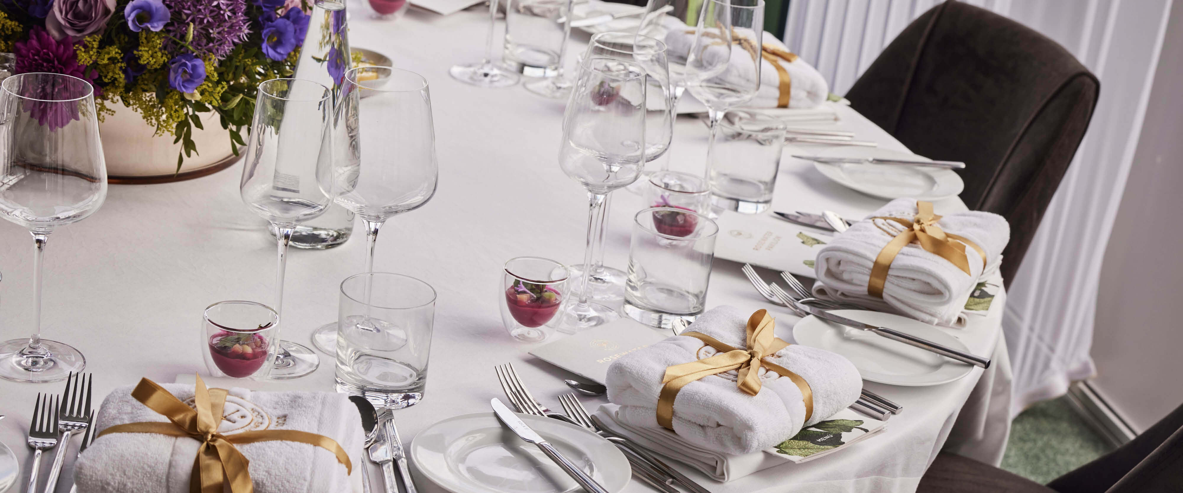 Table set for guests in Rosewater Pavilion  Private Dining with cutlery plates and flowers in at The Championships Wimbledon