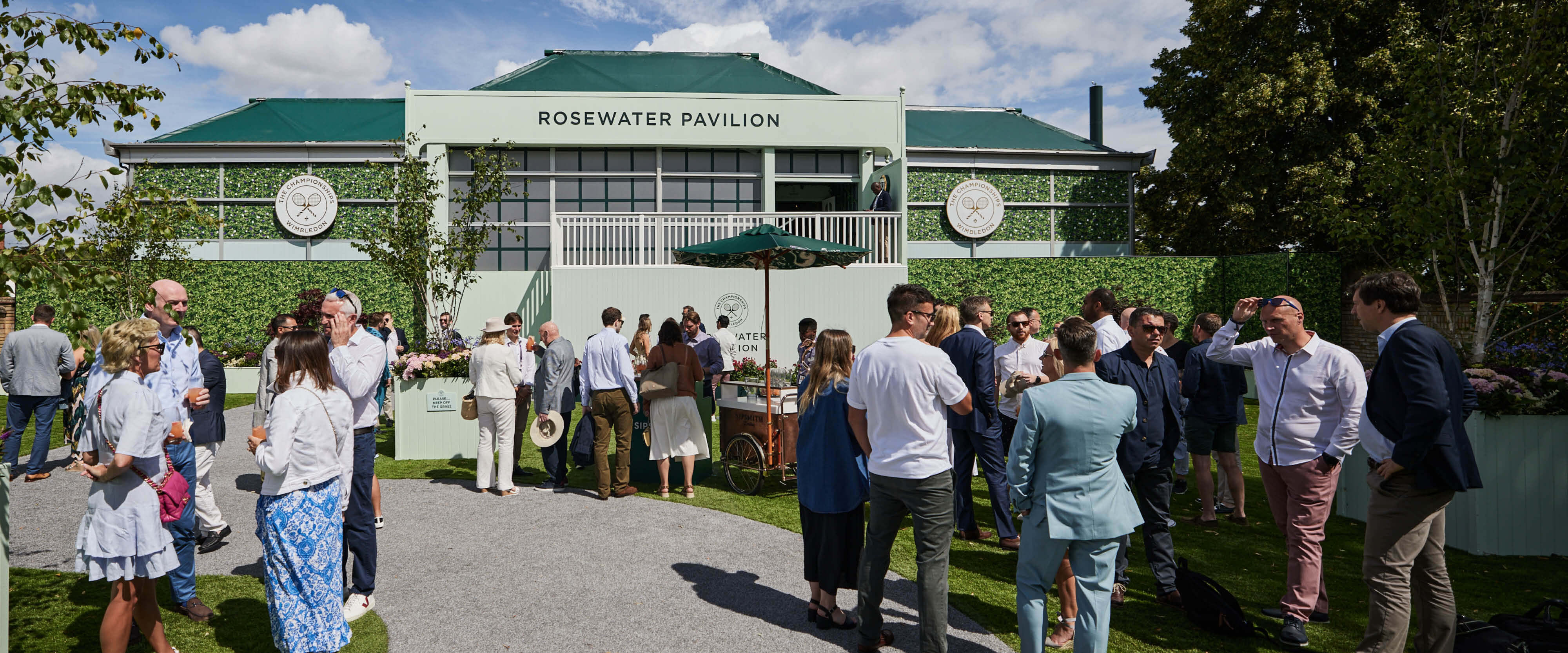Rosewater Pavilion hospitality facility with guests outside enjoying a welcome drink at The Championships Wimbledon